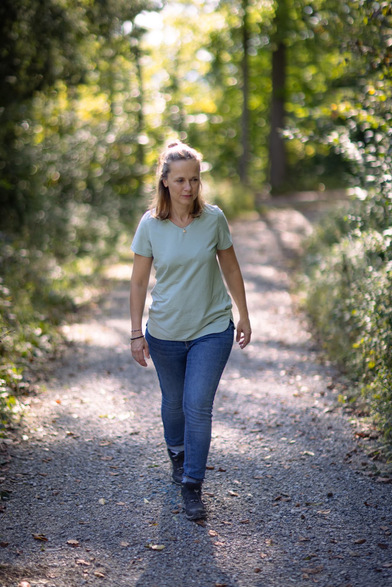 Die Gesundheitstrainerin auf einem sonnigen Waldweg